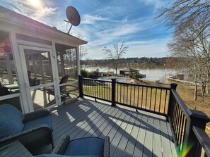 A covered deck with outdoor furniture, a satellite dish, and a view of a lake. - Sunset Cove-Sleeps 8-private pool-stunning views (Milledgeville)
