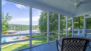 Un espace extérieur abrité, doté de grandes fenêtres donnant sur un lac et une piscine.
