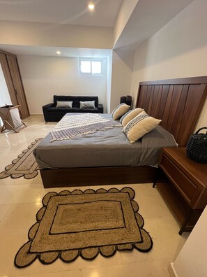 Un dormitorio con cama, mesita de noche, cabecera de madera, ventana y puerta.