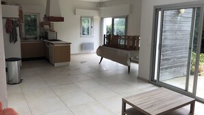 Une cuisine spacieuse avec un coin repas, une petite table et une porte-fenêtre coulissante donnant sur un balcon.