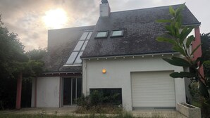 Une maison avec un toit en pente, un garage et un petit jardin.