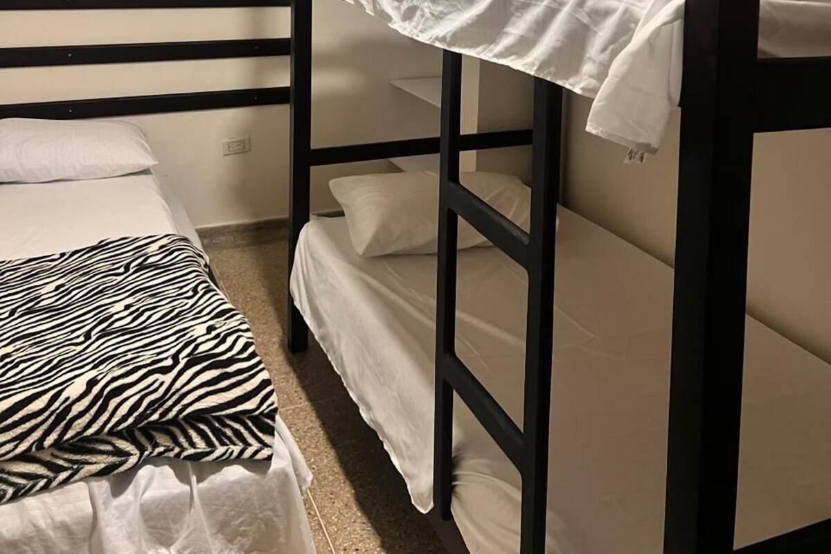 Una cama litera con ropa de cama blanca y una manta de estampado de cebra en la cama inferior.