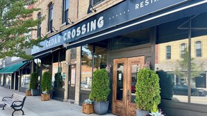 A restaurant named Cedar Crossing with a black awning, large windows, and potted plants at the entrance. - Pelican's Rock: 10 min walk to downtown, beach & park + Deck + Fire pit (Sturgeon Bay)