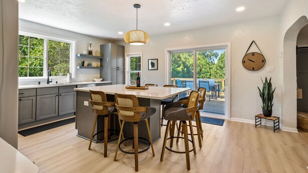 A modern kitchen with a central island, bar stools, and a hanging light fixture. - Pelican's Rock: 10 min walk to downtown, beach & park + Deck + Fire pit (Sturgeon Bay)