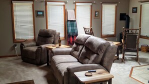 A cozy living room with a brown leather sofa, a wooden coffee table, and a wooden chair. - Woodland Hideaway a Cozy & Relaxing Finger Lakes 2 bedroom home in Naples NY (Naples)