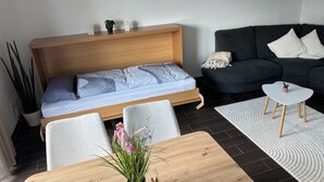 A modern room with a bed, a sofa, a small table, and a potted plant. - Cozy vacation apartment with sun terrace (Schlitz)