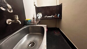 Une petite cuisine équipée d’un évier, d’une cuisinière et d’un miroir au-dessus du plan de travail.