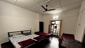 Une chambre de dortoir avec deux lits simples, une table en bois et un ventilateur de plafond.