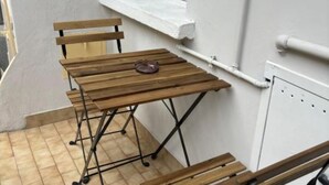 A small wooden table with a metal frame, positioned against a white wall with a window above it.