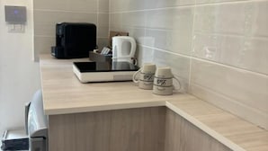 A modern kitchen with a coffee machine, a kettle, and two mugs on the counter.