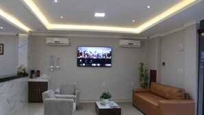 A modern living room with a flat-screen TV, two sofas, a coffee table, and a marble fireplace. - Hotel Estrela (Castanhal)