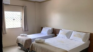 A hotel room with two beds, a window with curtains, a wooden table, and a tiled floor. - Hotel Estrela (Castanhal)