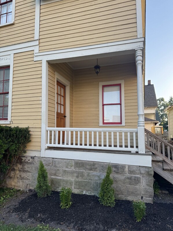 A two-story house with a front porch, a stone foundation, and a small garden area. - Remodeled Downtown Historic Home, close to beach, McMorran, Marina (Port Huron)