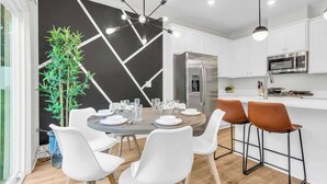 A modern kitchen with white cabinets, a stainless steel refrigerator, and a microwave.