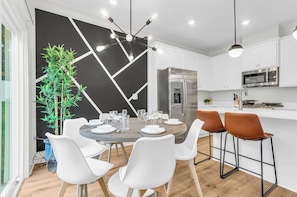 A modern kitchen with white cabinets, a stainless steel refrigerator, and a built-in microwave. - The Spartan Retreat | Luxe 3BR | Sleeps 10 (Spartanburg)