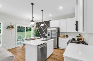 A modern kitchen with a central island, stainless steel appliances, and white cabinetry.