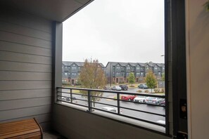 A balcony with a view of a parking lot and residential buildings. - Luxe Modern Loft, Great for Long Stays W/King Beds (Spartanburg)
