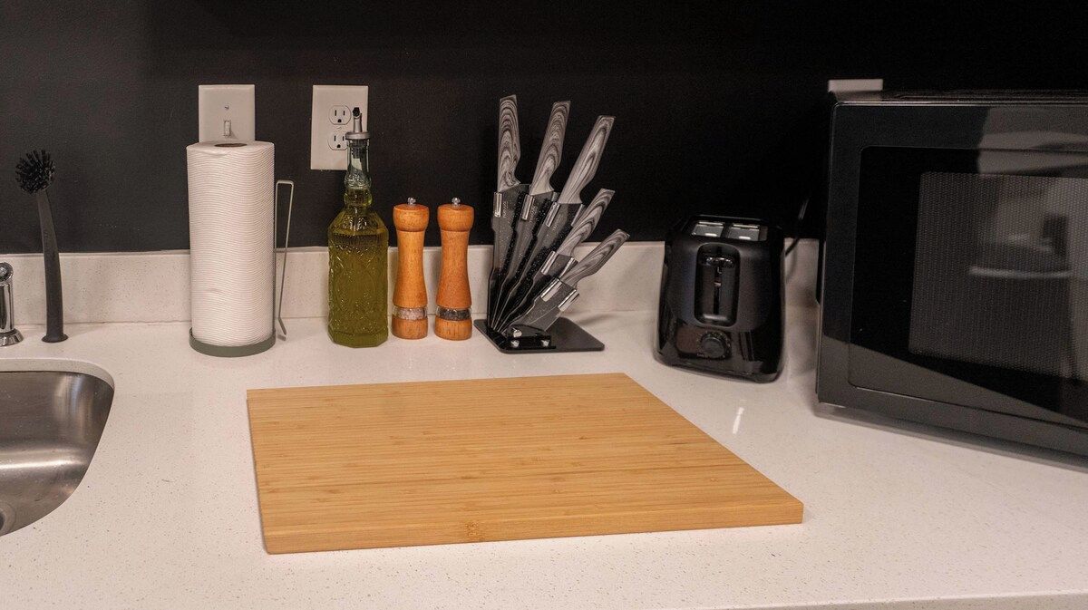 Eine Küchenarbeitsplatte mit Schneidebrett, Toaster, Mikrowelle und einem Messerblock.