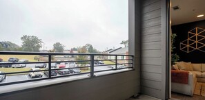 Un balcon donnant sur un parking et une rue.