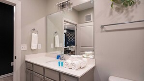 Une salle de bain moderne avec un lavabo blanc, un miroir et un porte-serviettes.