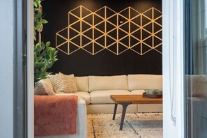A modern living room with a beige sofa, a wooden coffee table, and a geometric wall decoration. - Luxe Modern Loft, Great for Long Stays W/King Beds (Spartanburg)