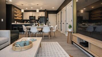 Una cocina moderna con armarios blancos, un comedor con mesa y sillas, y un televisor sobre un mueble de madera.