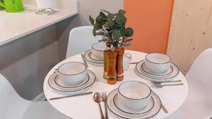 A round dining table set with white plates, bowls, and cutlery, accompanied by a vase with green foliage and two salt and pepper shakers. - Ideal for long stays, great location, King bed! (Spartanburg)