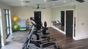 A spacious room with a ceiling fan, exercise equipment, and a large mirror. - Ideal for long stays, great location, King bed! (Spartanburg)