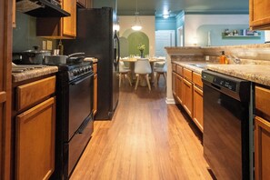 Una cocina con armarios de madera, un refrigerador negro, una estufa y un lavavajillas.