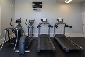 A gym with three treadmills, two elliptical machines, and a stationary bike.