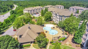 A residential complex with multiple apartment buildings, a swimming pool, and a parking area.