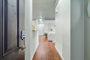 Ein Korridor mit Holzboden, einer weißen Tür und einer weißen Wand.