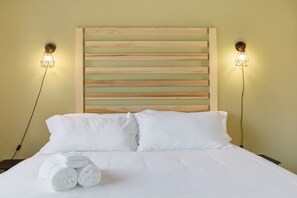Una habitación de hotel con una cama, dos lámparas de noche y un cabecero.