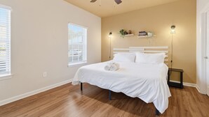 A bedroom with a bed, ceiling fan, bedside lamps, and a window.