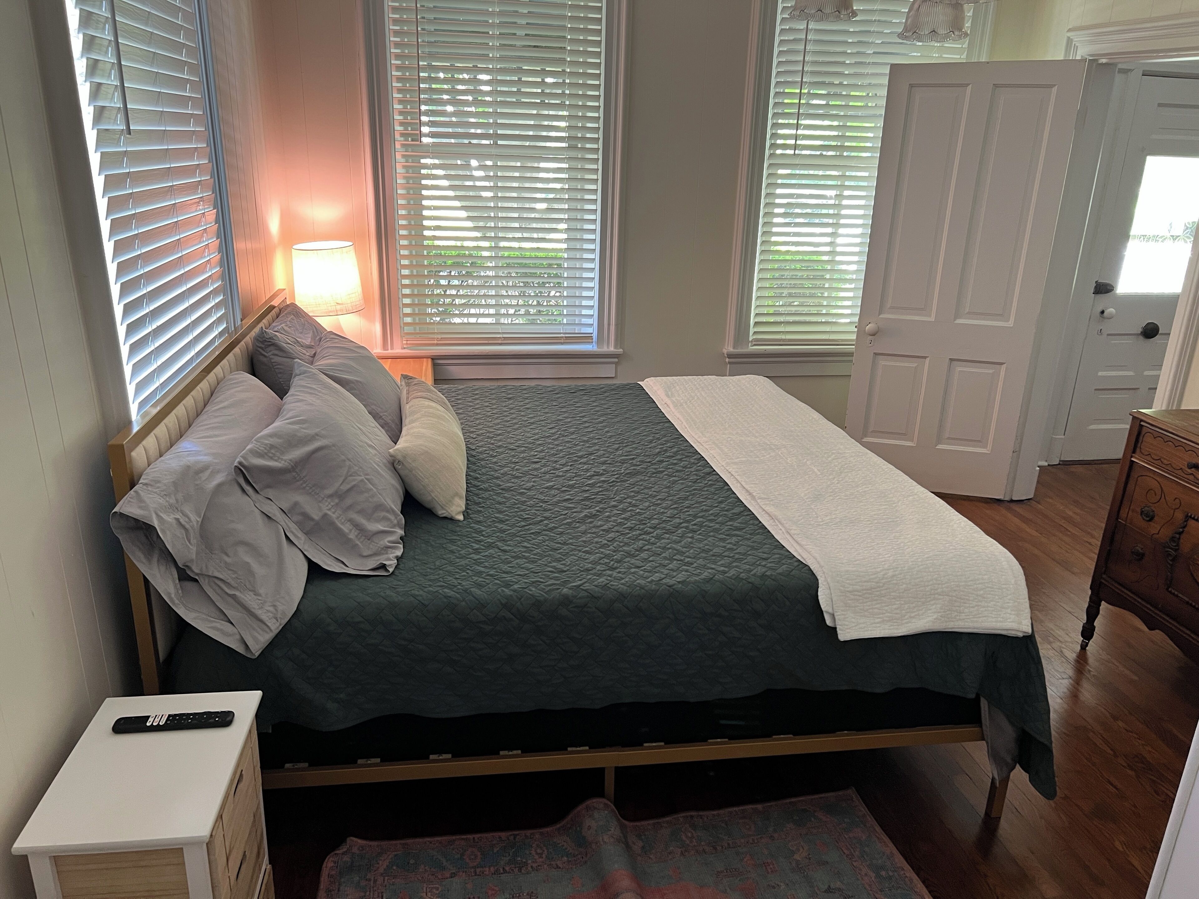 A bedroom with a bed, bedside lamp, and a dresser.