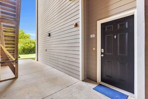 A residential entryway with a black door, a blue mat, and a staircase leading to an upper level. - Pool, Gym & Central Location! 2- King Beds (Spartanburg)