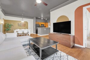 A modern living room with a sofa, a coffee table, and a flat-screen TV on a wooden cabinet.