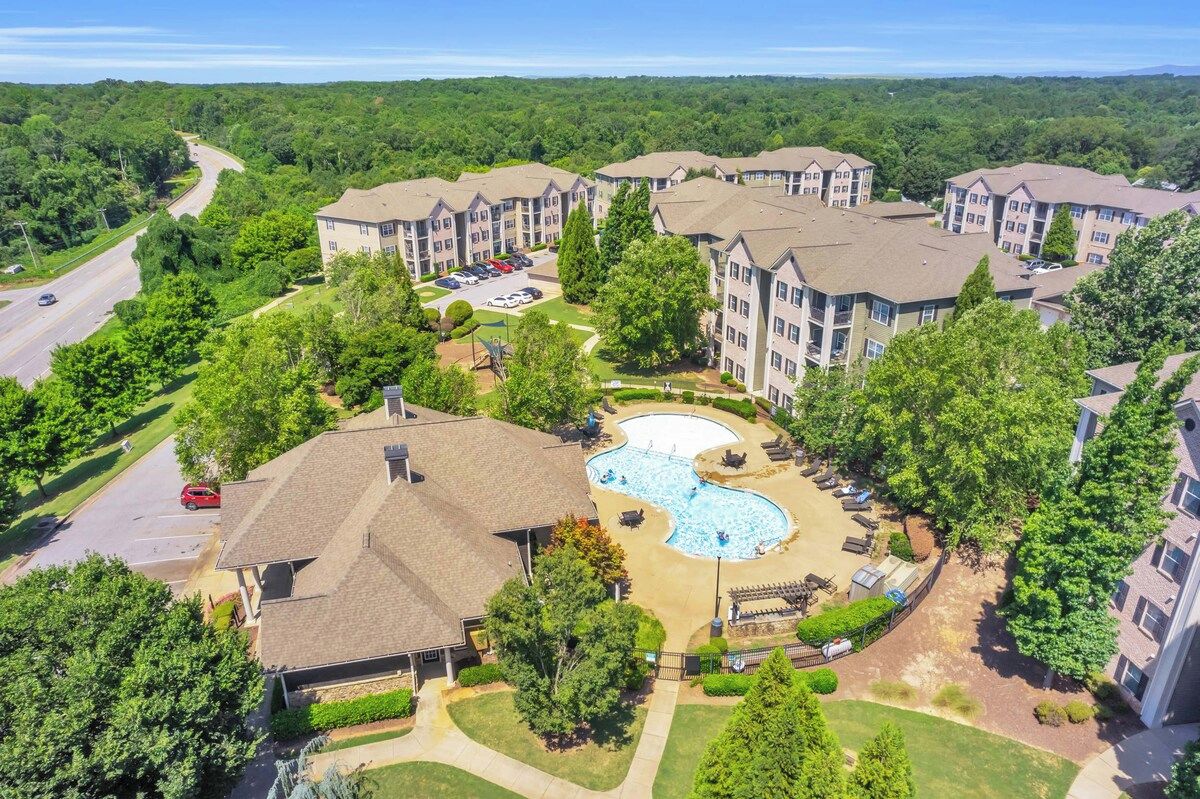 A residential complex with multiple apartment buildings, a swimming pool, and a parking area.