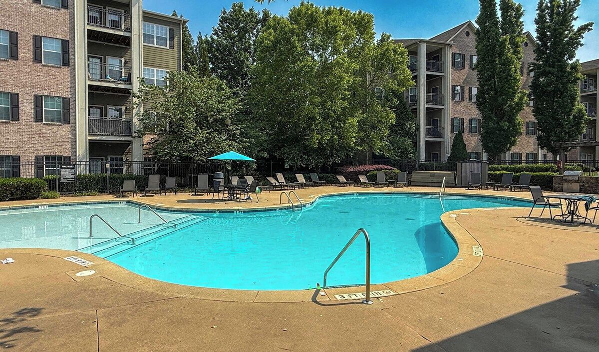 Ein Swimmingpool mit Liegestühlen und einem kleinen Sonnenschirm, umgeben von Wohngebäuden.