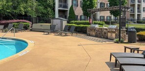A pool area with lounge chairs, a barbecue grill, and a small shed. - 3 King Beds, Perfect for Long Stays (Spartanburg)