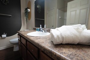 A bathroom with a granite countertop, white sink, and a towel rack.