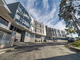 A modern building with multiple floors, large windows, and a gated entrance.