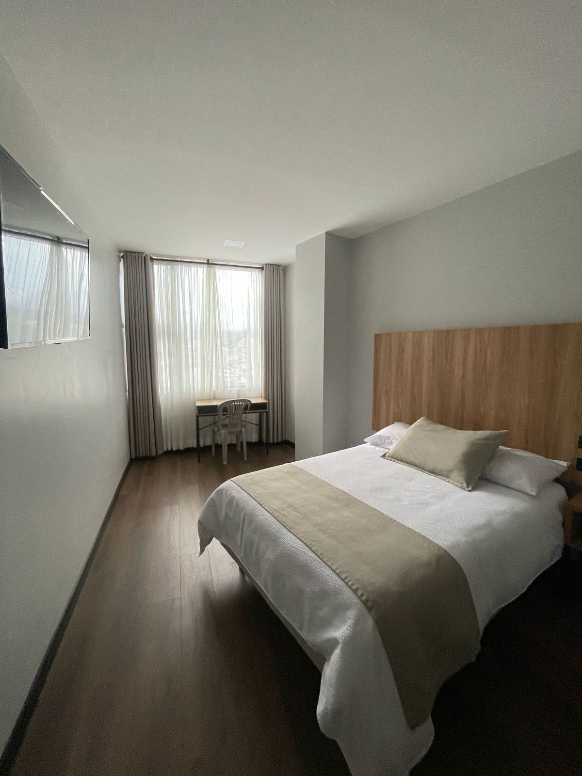 A hotel room with a bed, a desk, and a chair.