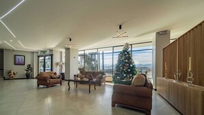 A spacious living area with a large Christmas tree, two sofas, a coffee table, and a wooden cabinet.