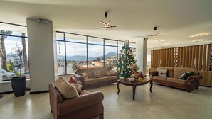 A spacious lobby with a large window, a Christmas tree, and two sofas.