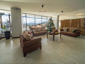 A spacious lobby with a large window, a Christmas tree, and two sofas. - Universitario Hotel (Loja)