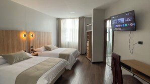 A hotel room with two beds, a desk, a TV, and a wardrobe.