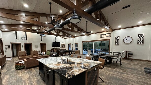 A spacious kitchen with a large island, wooden beams, and a dining area with a pool view. - Rippling Waters! 3 BD 2.5 BA Riverfront Home, 8 min. from airport.  Sleeps 11. (Mills River)