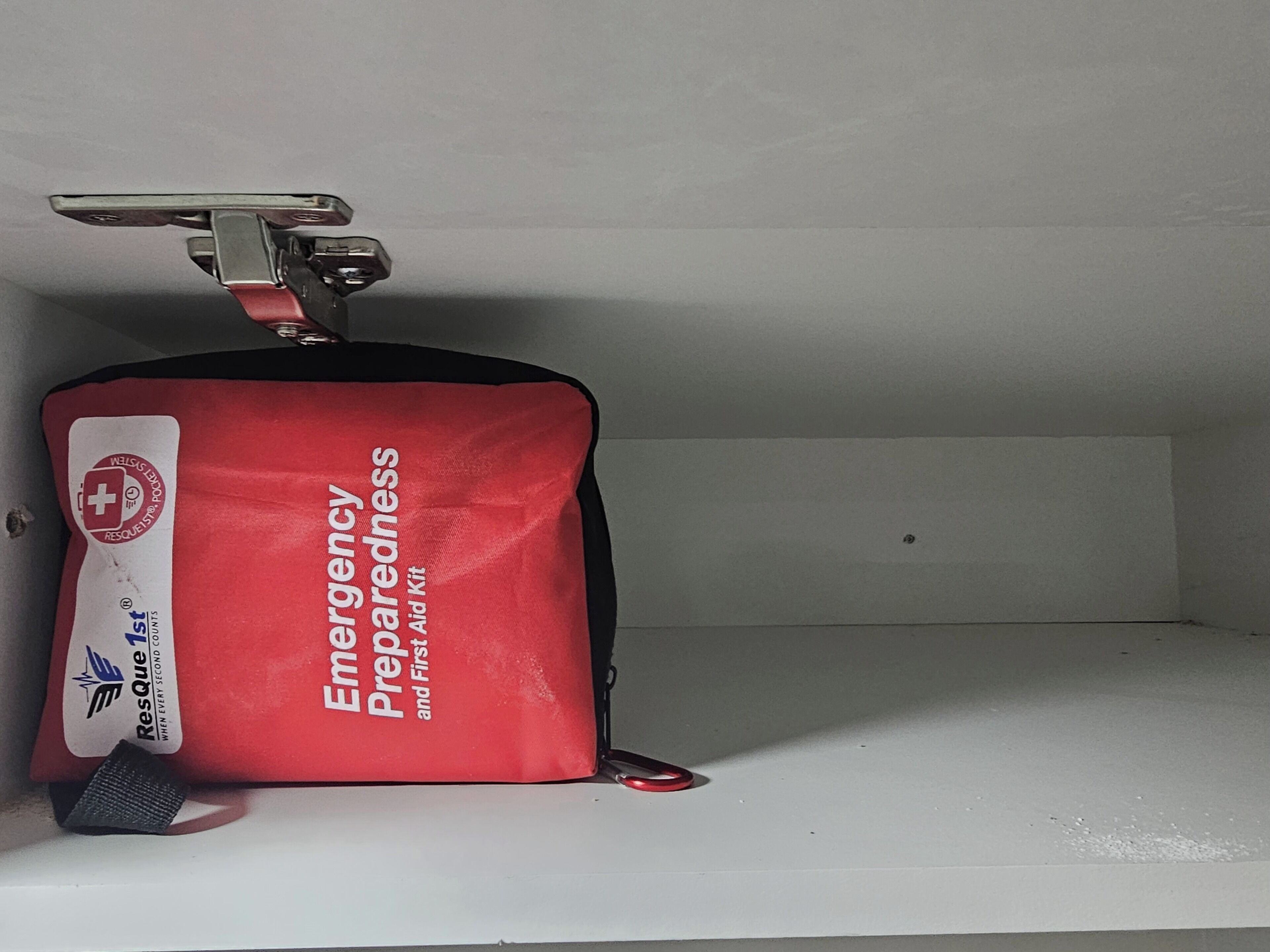 A red emergency preparedness kit in a white shelf.