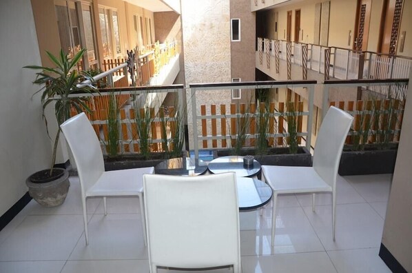 Enjoy a peaceful retreat on this balcony with a seating area and potted plants.
